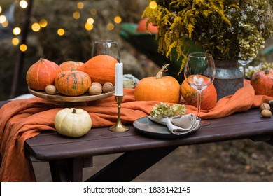 Fall themed holiday table setting arrangement for a seasonal party, glasses, pumpkins, candles, field flowers