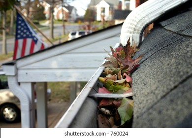 A Fall Tradition - Cleaning The Gutters Of Leaves. Here, We See Them Clogging The Gutters Of A Traditional Home. Narrow DOF Used For Advertising/clean Up Articles/etc.