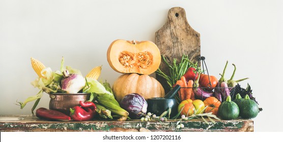 Fall Vegetarian Food Ingredients Variety. Assortment Of Autumn Vegetables For Healthy Cooking Over Rustic Cupboard, White Wall Background, Copy Space, Wide Composition. Local Market Organic Produce