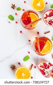 Fall and winter drinks. Warm refreshing cocktail with  pomegranate, oranges, cinnamon, spices and mint. On a white marble table. Copy space  top view