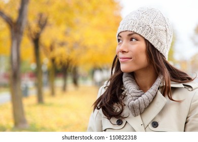 Fall Woman Portrait Of Woman Looking Sideways Smiling Serene. Beautiful Young Multiracial Woman Walking In Autumn In City Forest Park In Trench Coat.