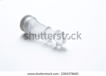 A fallen chess piece, the King figure, a symbol of defeat, despair, strategy gone wrong, and loss, lies isolated against a pure bright white background. Next to the chess piece is blank copy space.