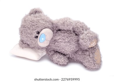 Fallen gray fur plush toy on white background. Teddy bear felling lonely laying down.  