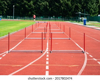 Fallen Hurdle On The Sprint Lane With Starting Blocks Against Blurry Background. Stadium With Two Hurdles Training Tracks. 