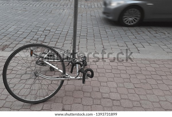 fallen parked \
bicycle lie on cobbled stone.\
