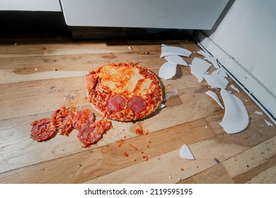 Fallen And Shatter Plate With Food In Kitchen. Dropped Pizza On Floor And Crashed Plate. Dirty Environment