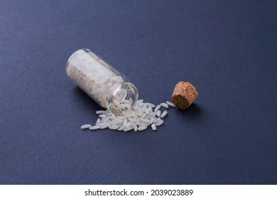 Fallen small opened mini bottle with cork filled with white rice.