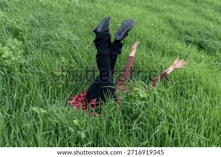 Fallen upside down person's legs stick up in deep green grass meadow