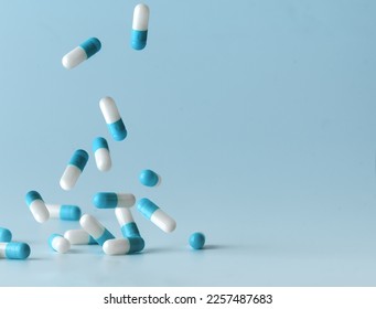 Falling blue medicine pill capsules on blue background. Antibiotics - Shutterstock ID 2257487683