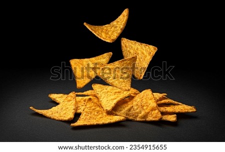 Falling corn chips, hot Mexican nachos isolated on black background