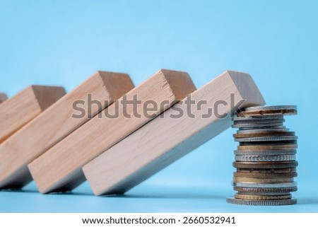 Falling Dominoes Are Stopped By A Stack Of Coins, Symbolizing Financial Stability Or Investment Defense
