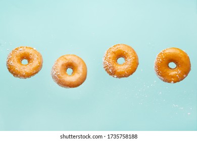 Falling Donuts With Coconut Flakes On A Light Blue Background. Freezing In Motion, Horizontal Photo