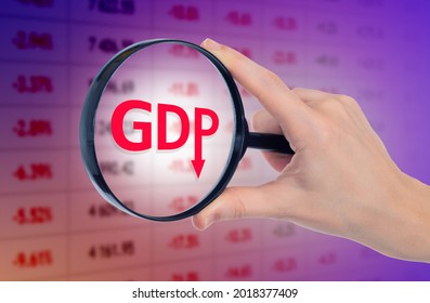 Falling GDP Logo. GDP Symbol Under Magnifying Glass. Loupe In Hand Of Man. Blurred Quotes In Background. Metaphor Of Economic Crisis. Deteriorating Economic Performance. Economic Depression