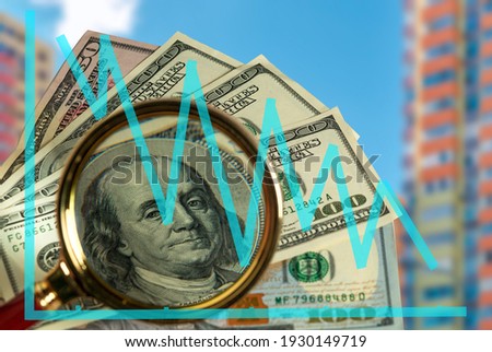 Falling graph against the background of dollars and a magnifying glass. US economy. Economic decline in America. Decrease in profits from real estate. Recession.