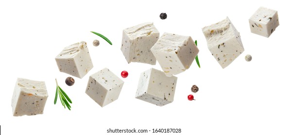 Falling greek feta cubes with herbs and spices, diced soft cheese isolated on white background