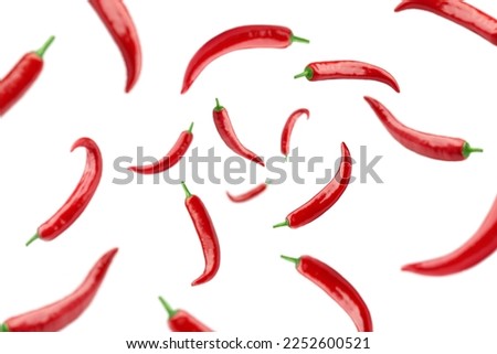 Falling red hot chili peppers isolated on white background, selective focus