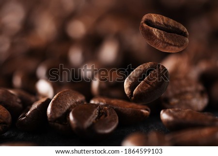 Falling roasted coffee beans background with copy space. Coffee beans in the factory. Coffee beans fall onto the table.