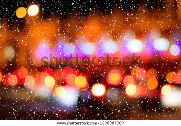 Falling snow against the background of blurry
lights of headlights of cars and the night city. Winter snowfall
concept. Abstract bright
bokeh.