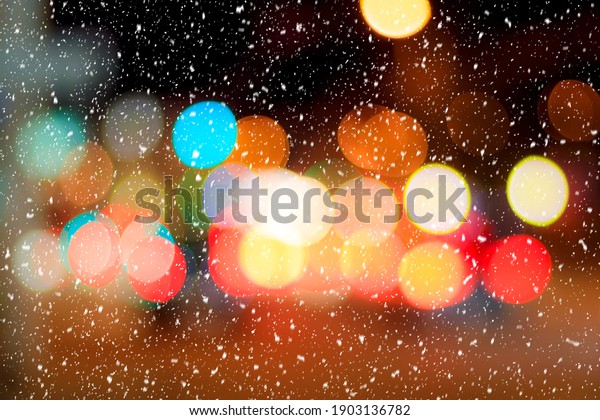 Falling snow against the background of blurry
lights of headlights of cars and the night city. Winter snowfall
concept. Abstract bright
bokeh.