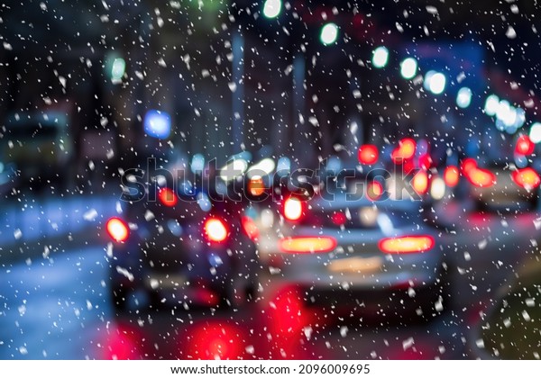 Falling\
snow on the background of cars with the headlights on at night. The\
concept of the first snow or snowfall in\
winter.