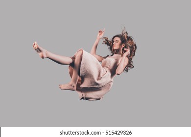 Falling to somewhere. Studio shot of attractive young woman hovering in air