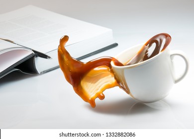 Falling and spilling of a cup of coffee on top of a desk with an open book
