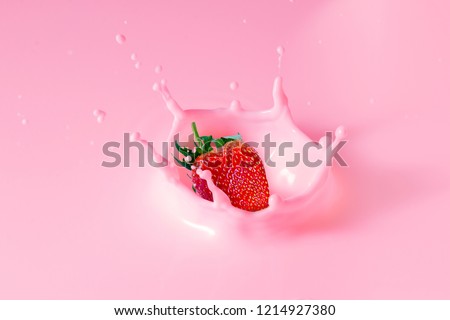falling strawberry is splashing into milk