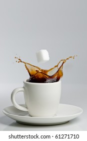 Falling Sugar Cube Into Splashing Black Coffee In White Cup.