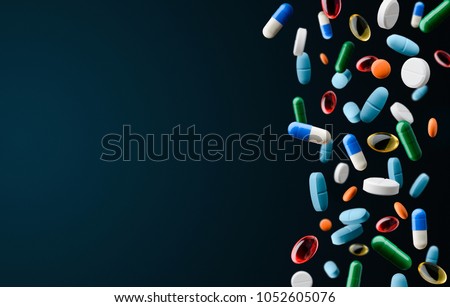Falling tablets and capsules on dark blue background. Medications, vitamins and oils. Smart and healthy lifestyle.
