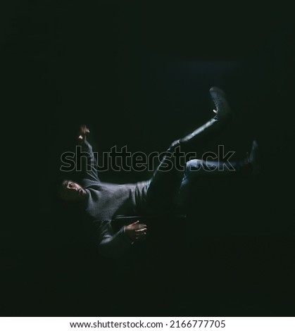 Falling your dream Thats fear of losing control. Shot of a young man falling against a dark background.