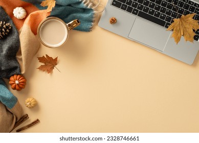 Fall-themed workspace arrangement. Top view of laptop, mug of steaming coffee, cozy plaid, petite pumpkins, golden leaves, pine cone, cinnamon on pastel beige surface, with empty area for text or ad - Powered by Shutterstock