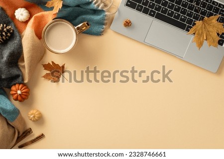 Fall-themed workspace arrangement. Top view of laptop, mug of steaming coffee, cozy plaid, petite pumpkins, golden leaves, pine cone, cinnamon on pastel beige surface, with empty area for text or ad