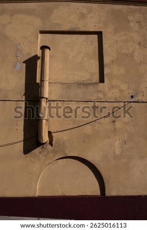 The false arch and the window on the wall of the building are connected into a single composition by a tin pipe 