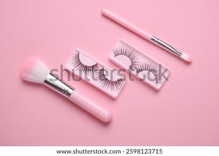 False eyelashes and makeup brushes on pink background. Beauty concept