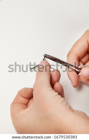 False eyelashes work process, scissors, glue, hands on a white background