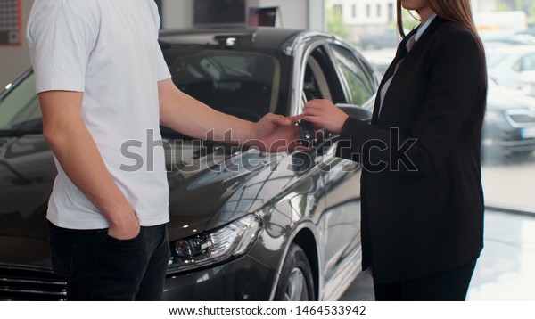 Famale hand gives a car keys to male hand in the\
car dealership close up. Unrecognized auto seller and a woman who\
bought a vehicle shake\
hands.