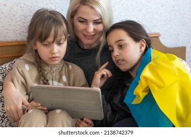 Families against war  mother   two daughters are reading and the flag ukraine in bed 