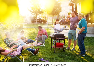 Familly Gathered And Is Having A Picnic Toasting Talking And Grilling In Their Backyard On A Beautiful Summer Day.