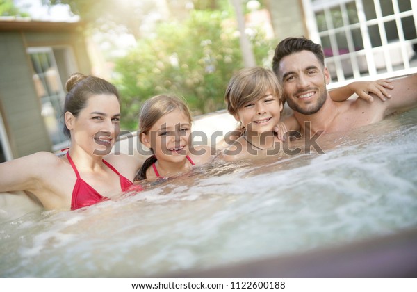 Family of 4 enjoying
bath in spa hot tub