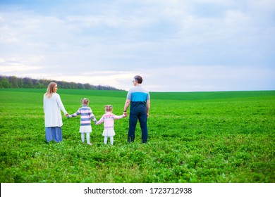 A Family Of 4 Looks Ahead And Into The Distance. Back View. The Concept Of Looking To The Future Together. Family Concept