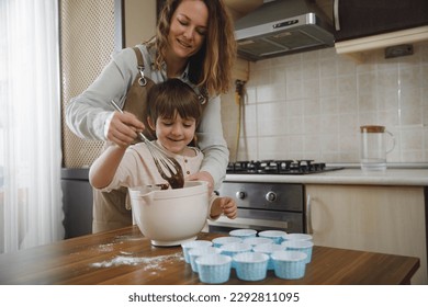 Family activities for kids at home. Mother and son making homemade cupcakes, preparing dough for muffins at the domestic kitchen. - Powered by Shutterstock