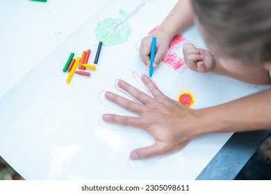 Family activity drawing son using crayons to draw father's hand - Powered by Shutterstock