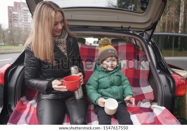 Family\
adventure - family on autumn camp. Young beauty mom and little\
child had picnic in back of car near the fall\
park