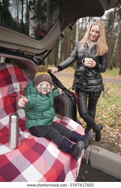 Family
adventure - family on autumn camp. Young beauty mom and little
child had picnic in back of car near the fall
park
