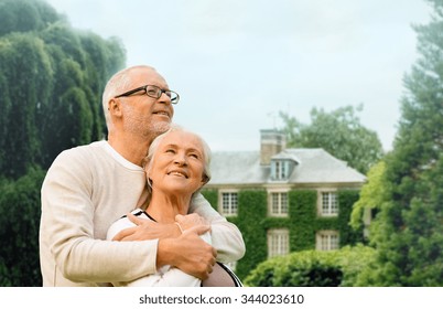 Family, Age, Home, Real Estate And People Concept - Happy Senior Couple Hugging Over Living House Background