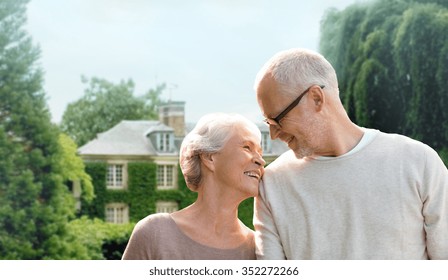 Family, Age, Home, Real Estate And People Concept - Happy Senior Couple Hugging Over Living House Background