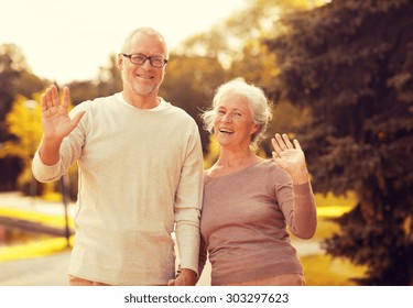 family, age, tourism, gesture and people concept - senior couple waving hands in city park