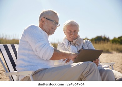 family, age, travel, tourism and people concept - happy senior couple with tablet pc computer resting in folding chairs on summer beach - Powered by Shutterstock