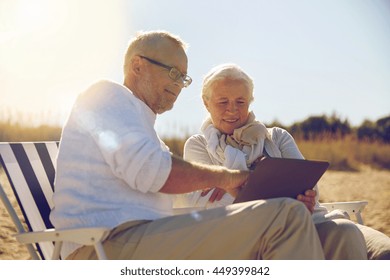 family, age, travel, tourism and people concept - happy senior couple with tablet pc computer resting in folding chairs on summer beach - Powered by Shutterstock