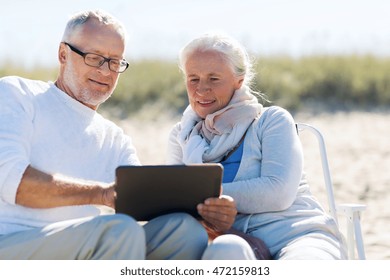 family, age, travel, tourism and people concept - happy senior couple with tablet pc computer sitting on deck chairs on summer beach - Powered by Shutterstock